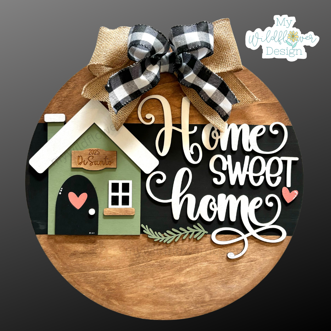 Decorative sign with 'Home Sweet Home' text and a small house design, featuring a plaid bow on a dark background.