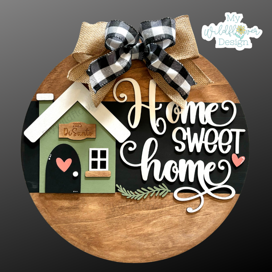 Decorative sign with 'Home Sweet Home' text and a small house design, featuring a plaid bow on a dark background.