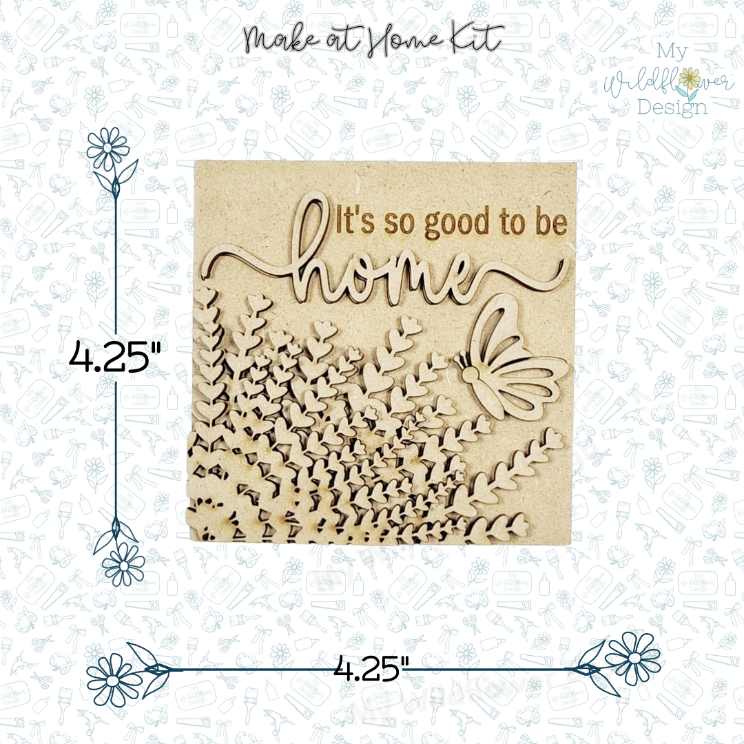 Wooden cutout with 'It's so good to be home' text on a white background with floral designs.